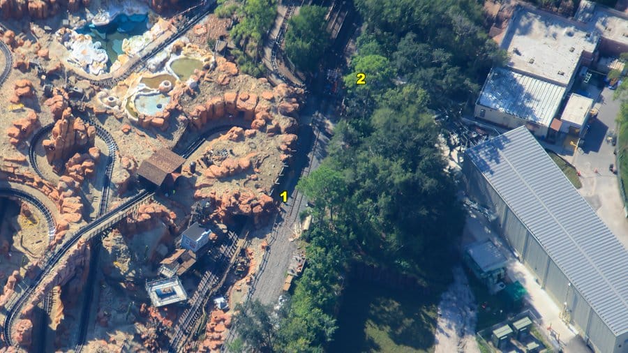 Aerial view of Magic Kingdom roller coaster, buildings, trees, and two numbered locations along a pathway.