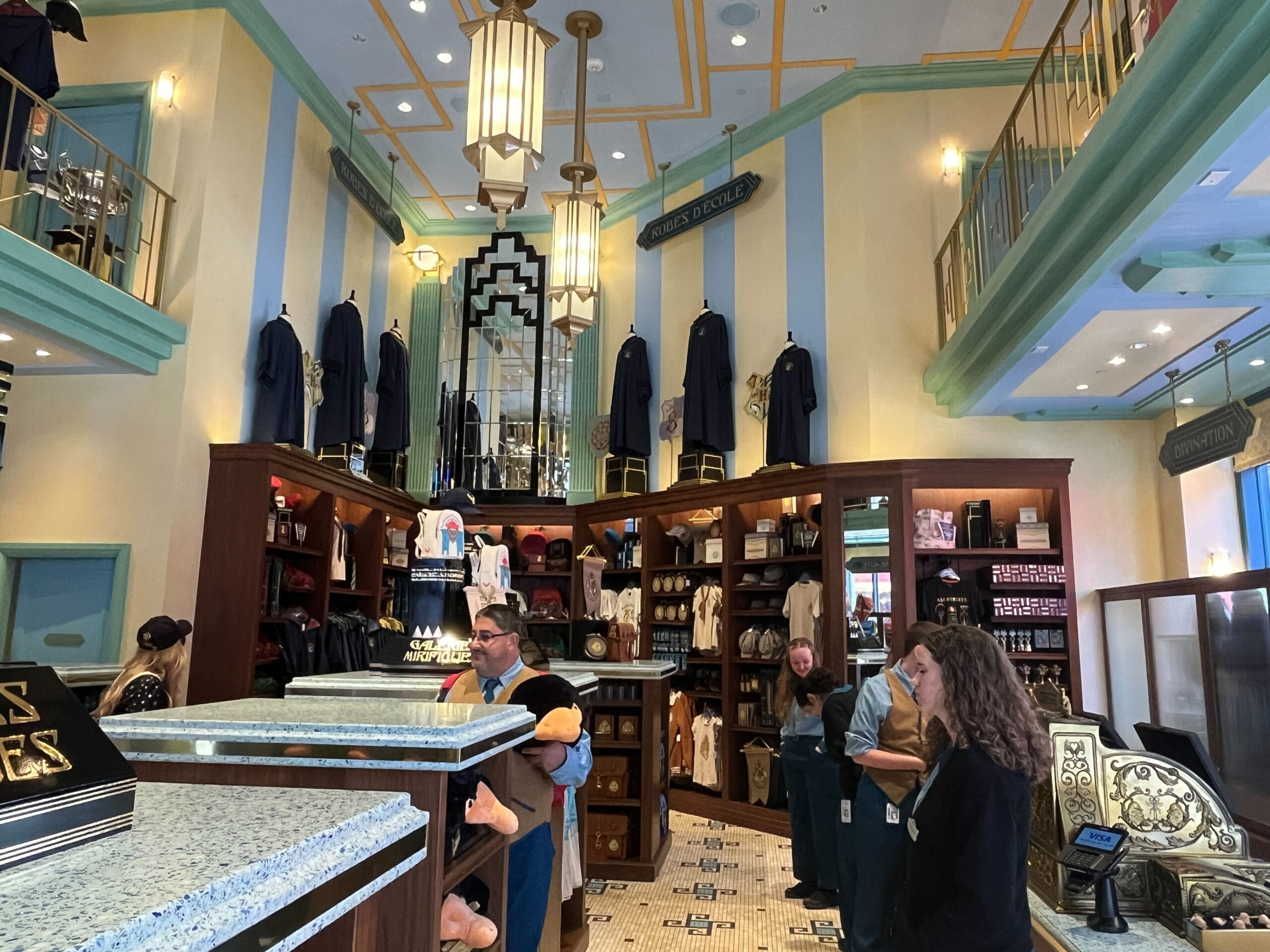 A Harry Potter-themed store interior, Les Galeries Mirifiques, with merchandise and decorative Hogwarts house robes on display.
