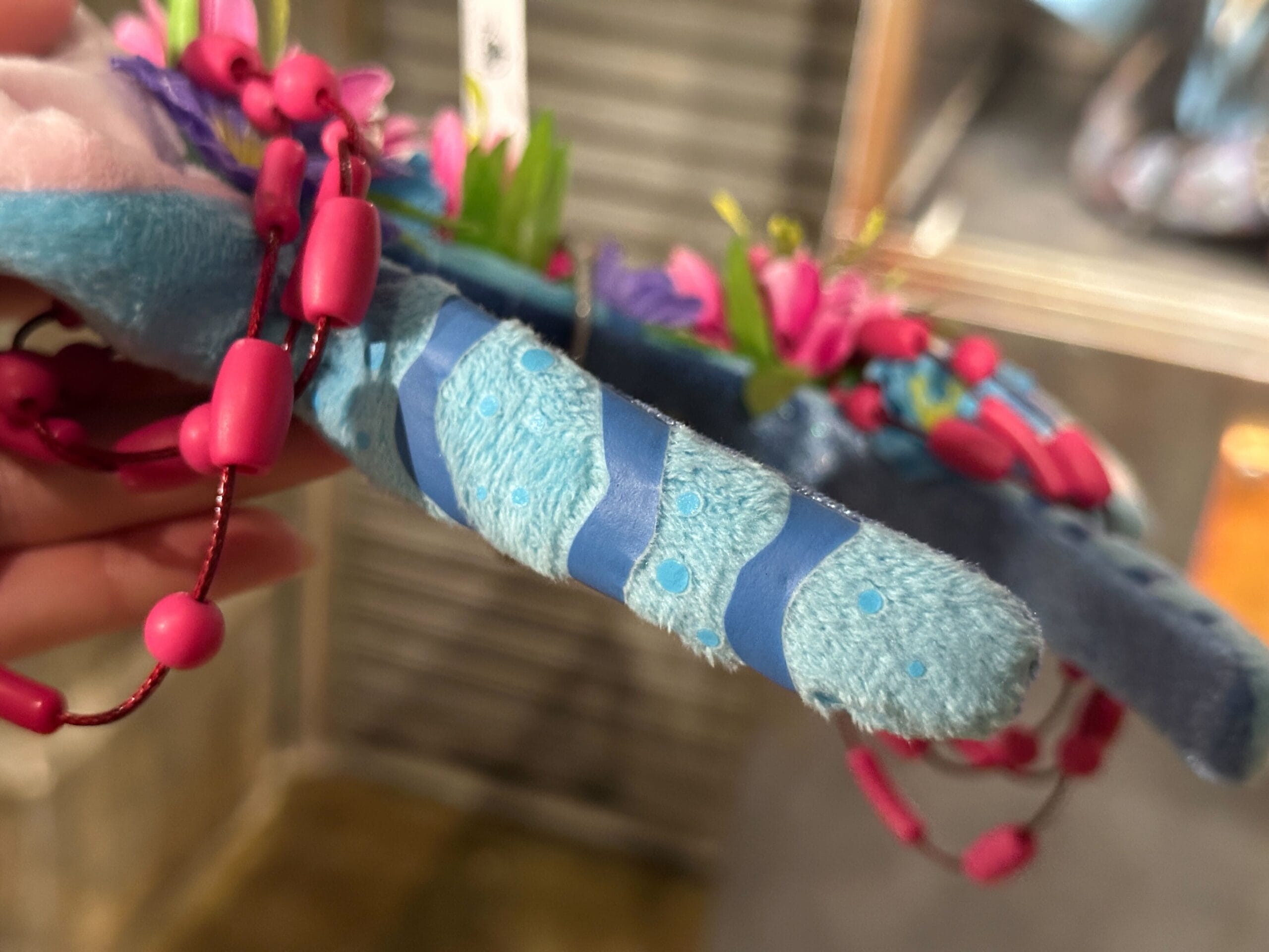 Close-up of a blue Ear Headband inspired by Pandora World of Avatar, with stripes, pink beads, and floral decorations.
